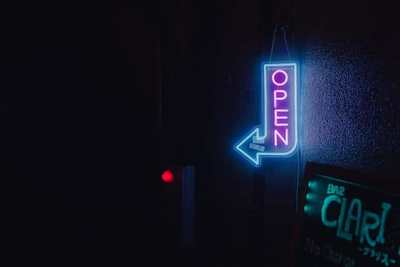 Neon open sign glowing in a dark shop window